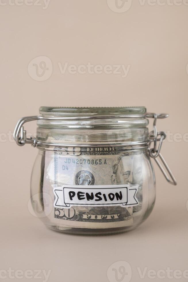 Glass jar full of American currency dollars cash banknote with text PENSION. Preparation saving money. Moderate consumption and economy. Collecting money photo