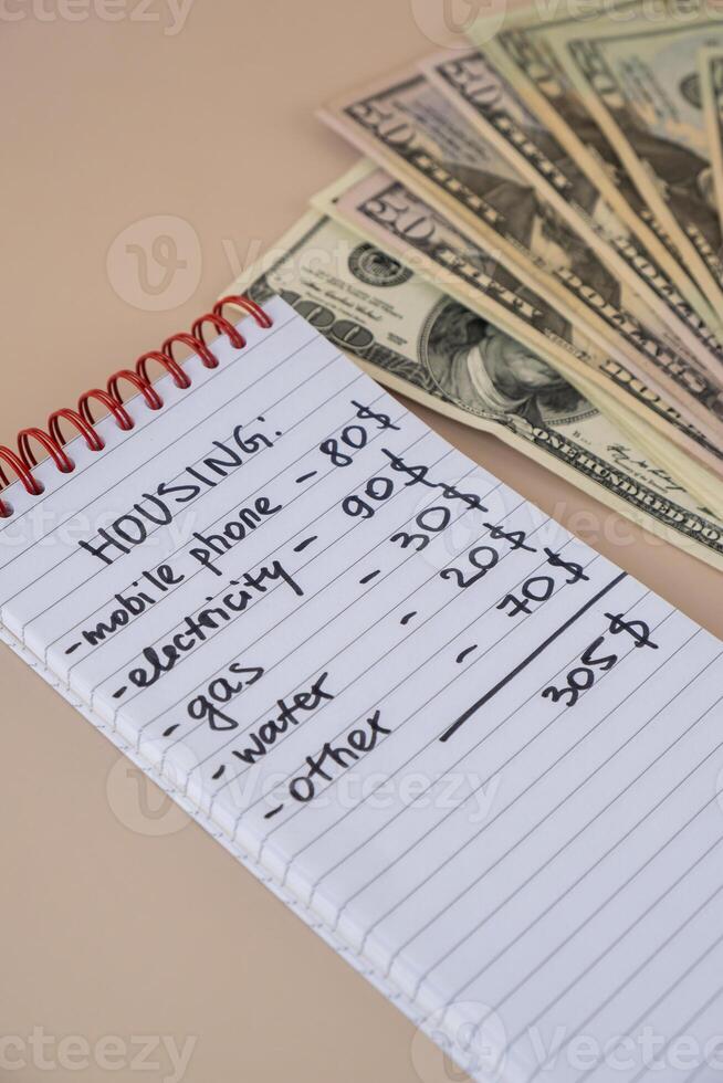 Dollar cash money with notebook handwritten housing expenses. Counting bills for electricity, gas, water. Concept of Efficient Consumption and Economy. Spending habits photo