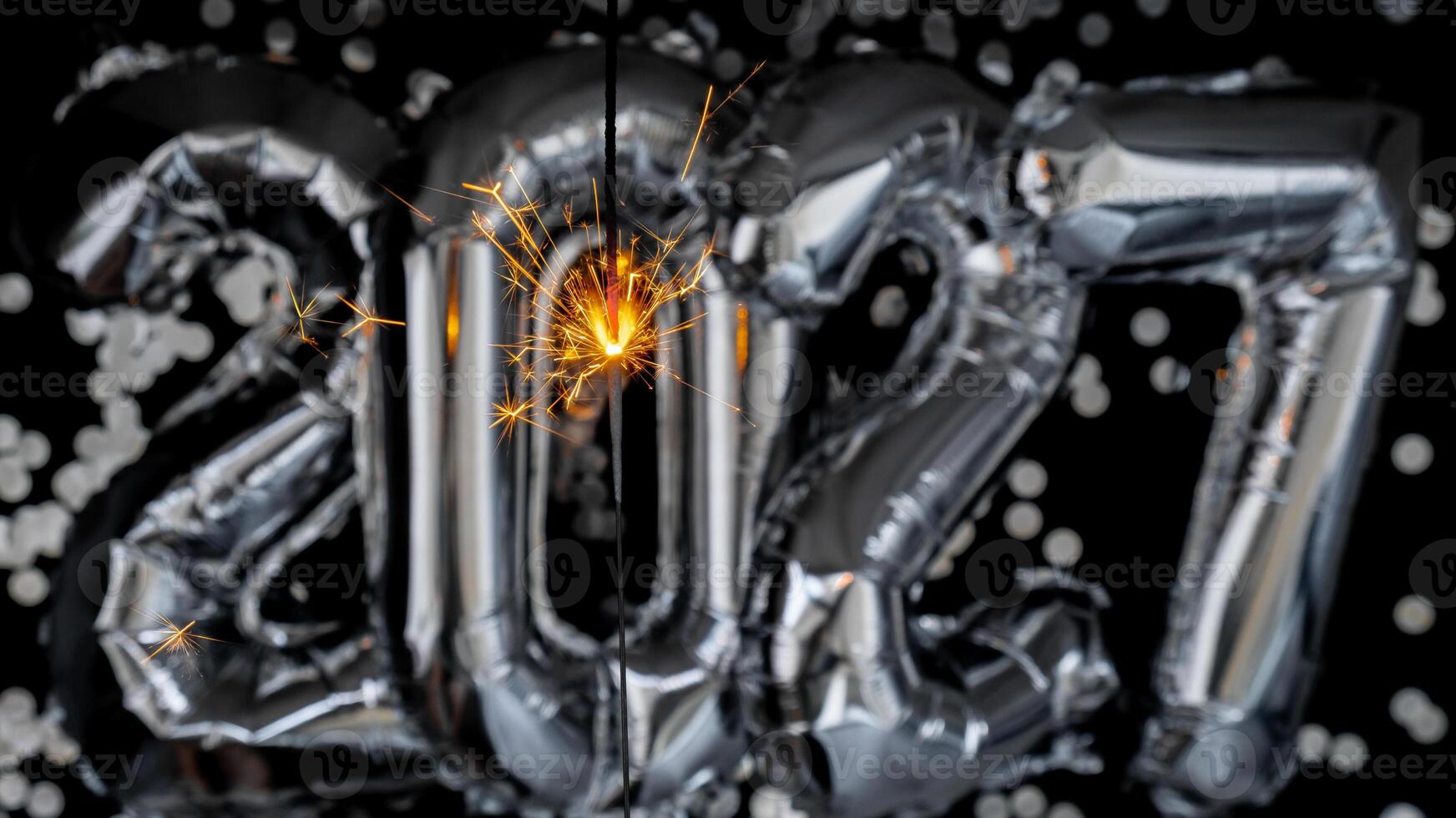 Happy new year 2027 metallic balloons with confetti and sparkler firework Bengal lights on dark black background. Greeting card silver foil balloons numbers Christmas holiday concept. Celebration party congratulation decoration photo