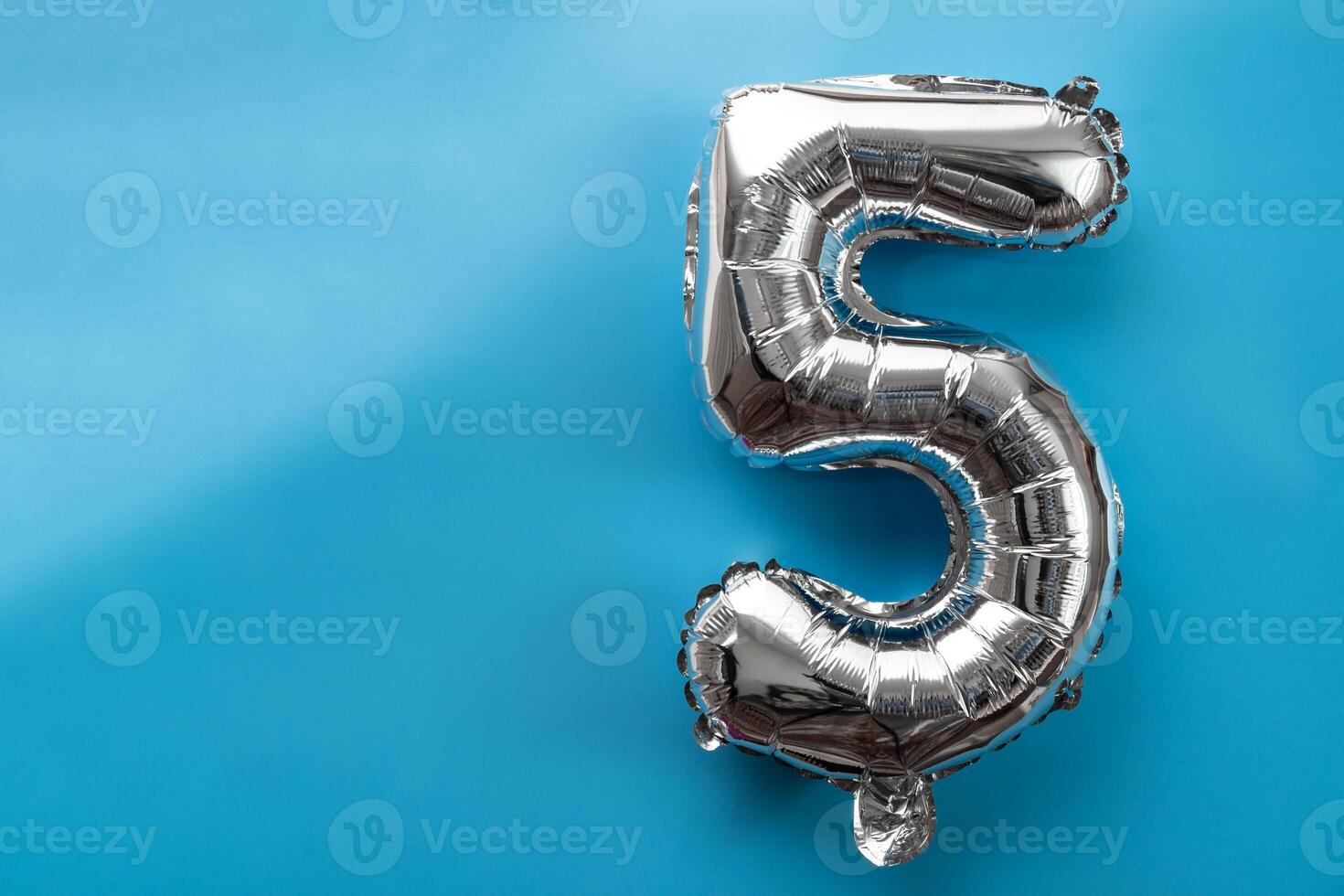 5 five metallic balloon isolated on blue background. Greeting card silver foil balloon number Happy birthday holiday concept. Copy space for text. Celebration party congratulation decoration photo