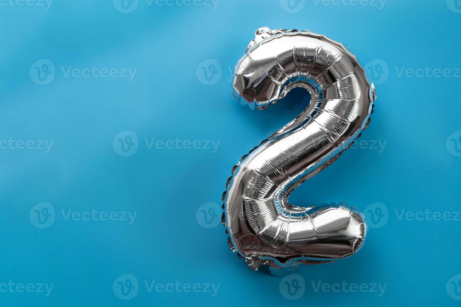 2 two metallic balloon isolated on blue background. Greeting card silver foil balloon number Happy birthday holiday concept. Copy space for text. Celebration party congratulation decoration photo