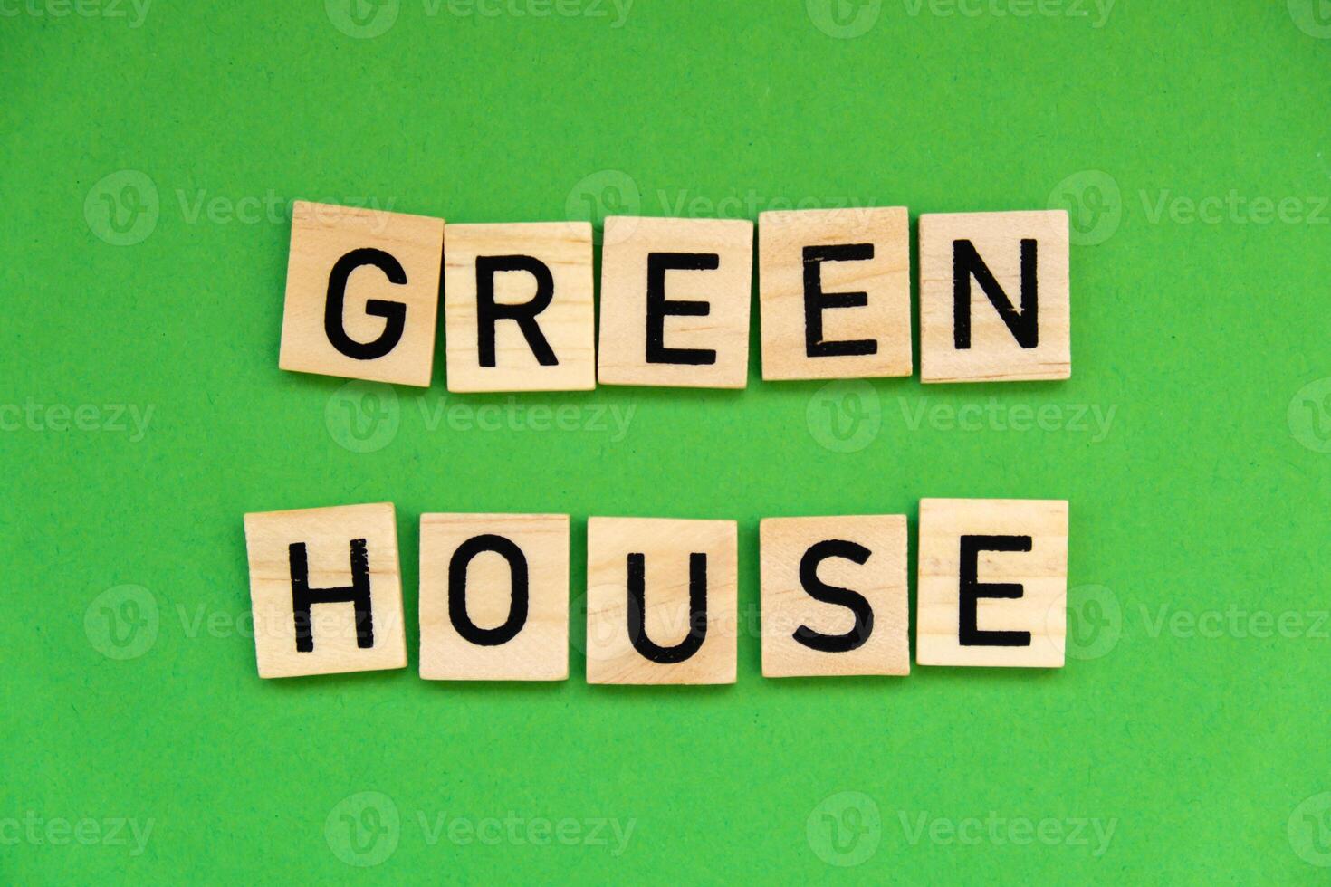 Green house text on wooden blocks on green background. Ecological concept Sustainable responsible living. Copy space. Single word photo