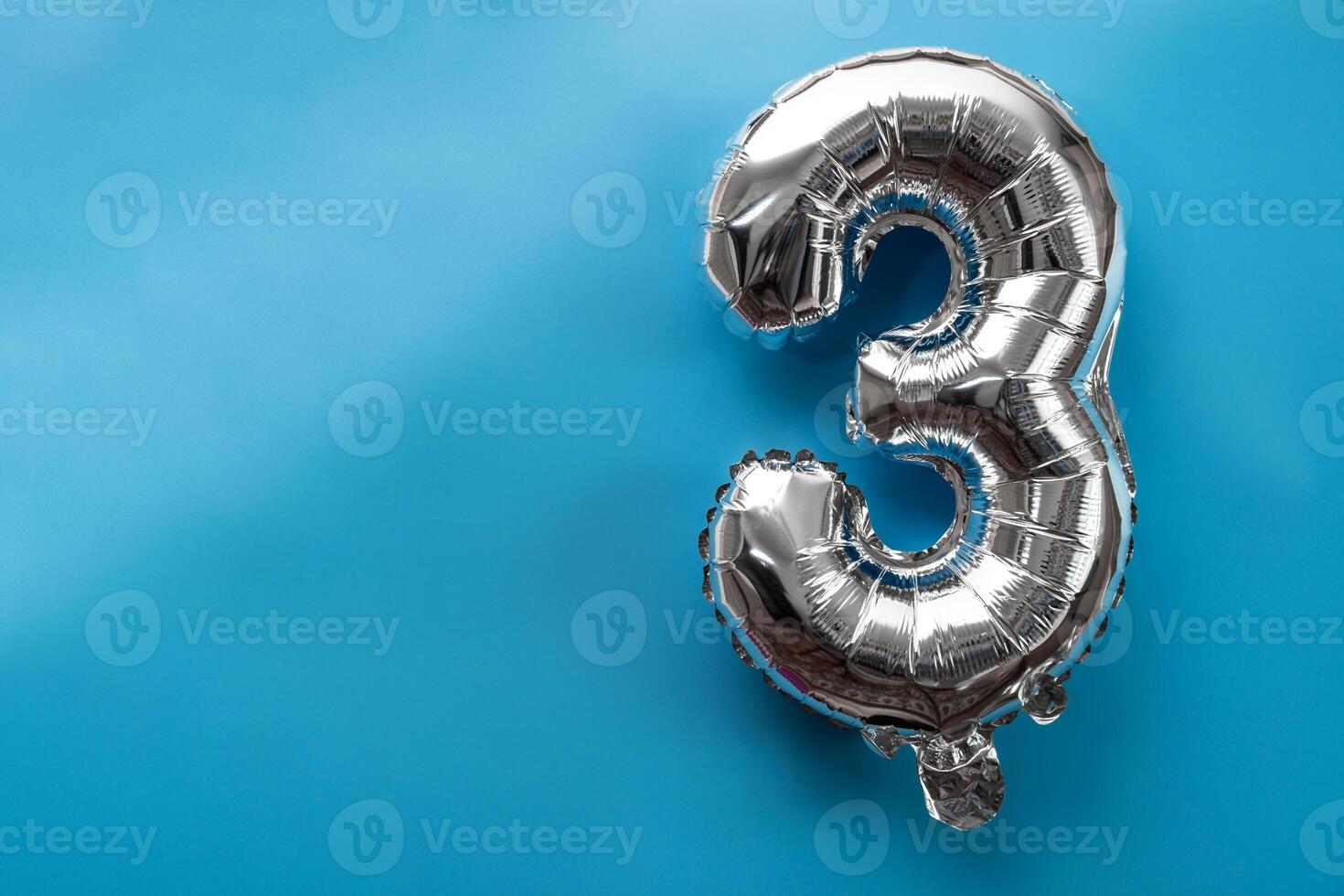 3 three metallic balloon isolated on blue background. Greeting card silver foil balloon number Happy birthday holiday concept. Copy space for text. Celebration party congratulation decoration photo
