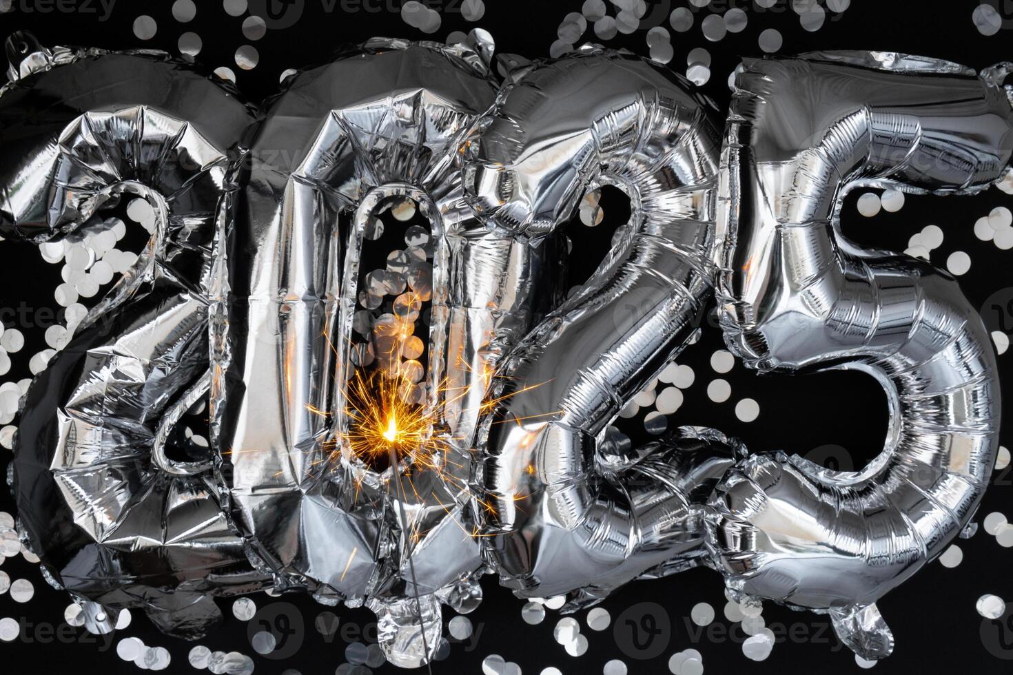 Happy new year 2025 metallic balloons with confetti and sparkler firework Bengal lights on dark black background. Greeting card silver foil balloons numbers Christmas holiday concept. Celebration party congratulation decoration photo