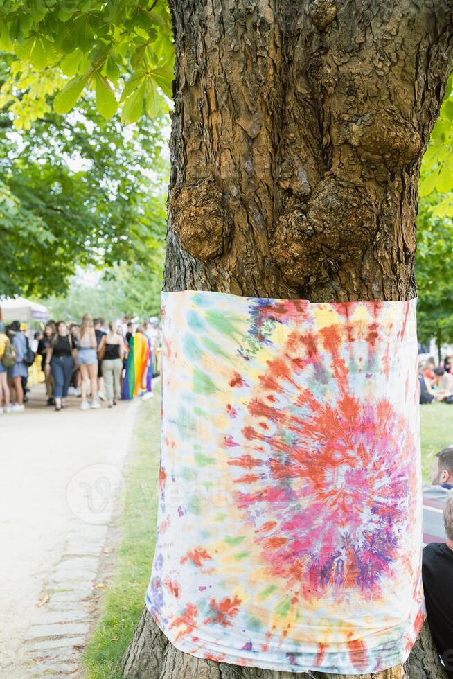 Tie dye cloth colorful flag hanging from tree, outdoor summer festival photo