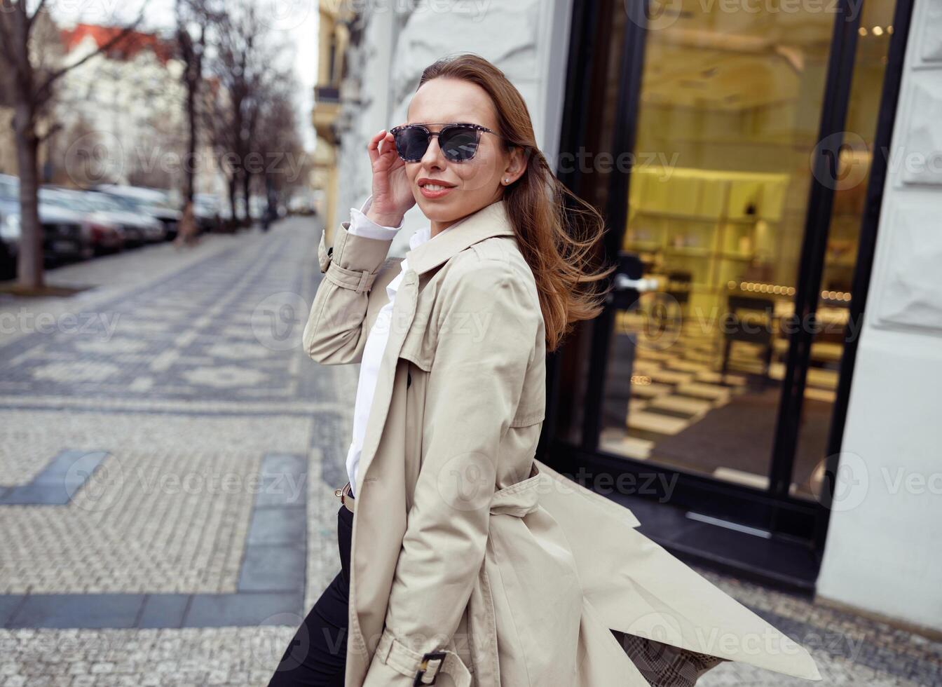 contento de moda mujer en Gafas de sol cruce el calle y mirando a cámara foto