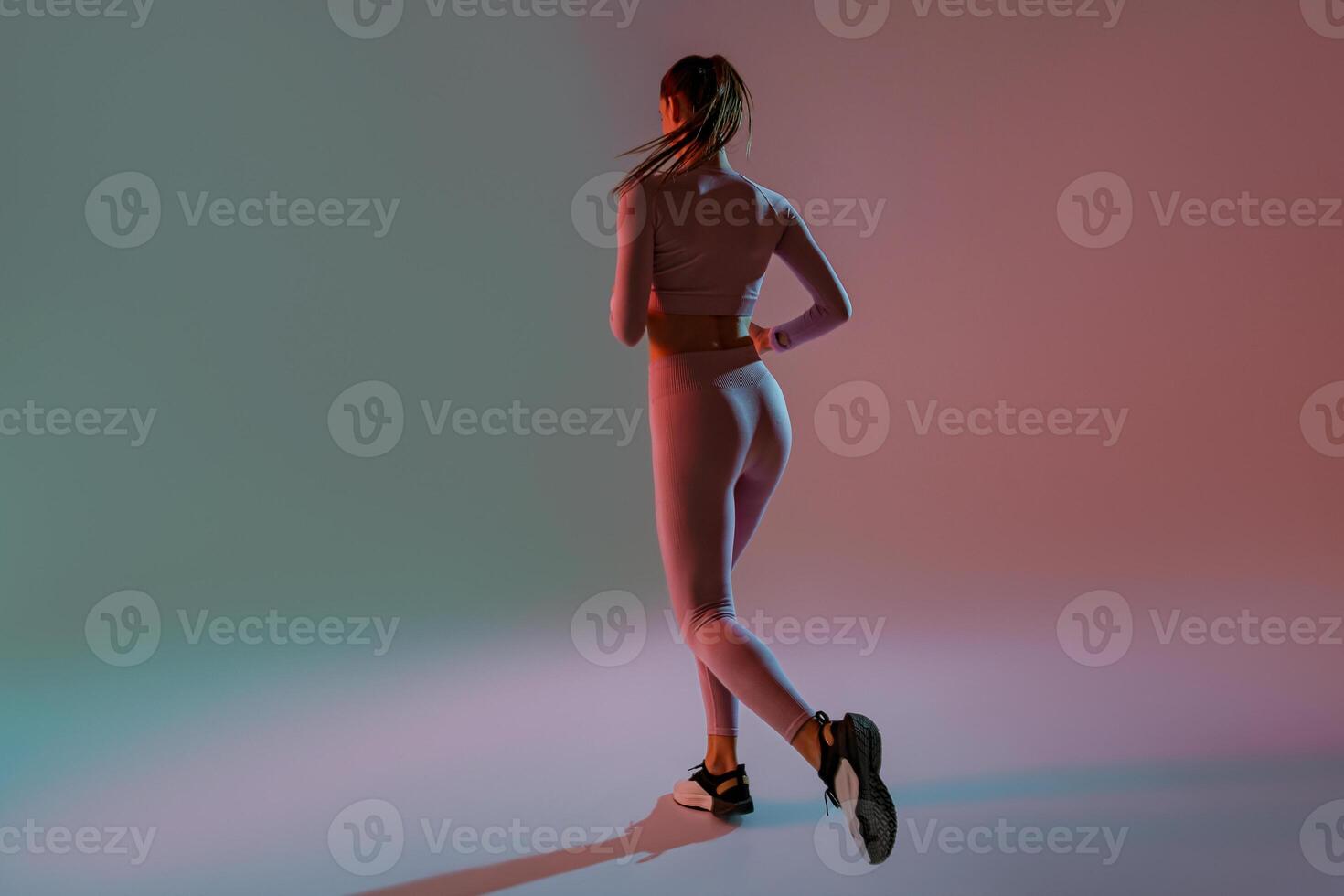 Back view of sporty woman running in Mid-Air exercising during cardio workout over studio background photo