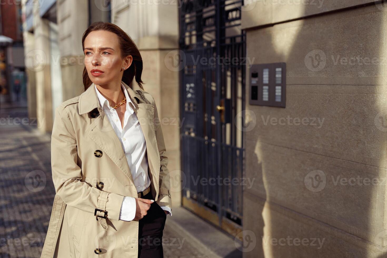 Attractive woman in coat crossing the city street and looking at side. Blurred background photo