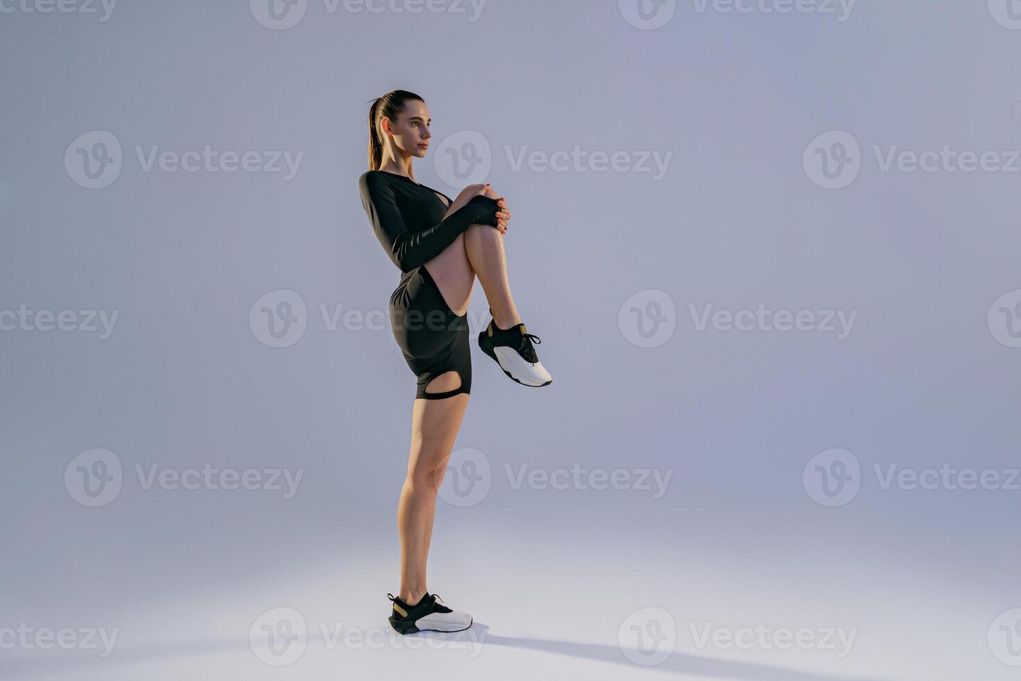 Focused sporty woman doing warm-up before training session in gym on studio background photo