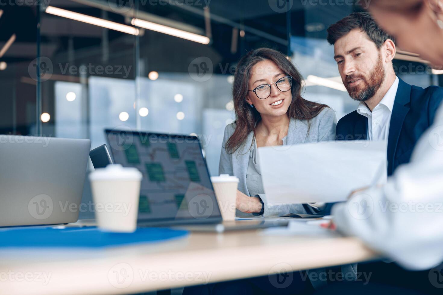 Close up of smiling businessmen discussing documents with graphs and charts in a modern office photo