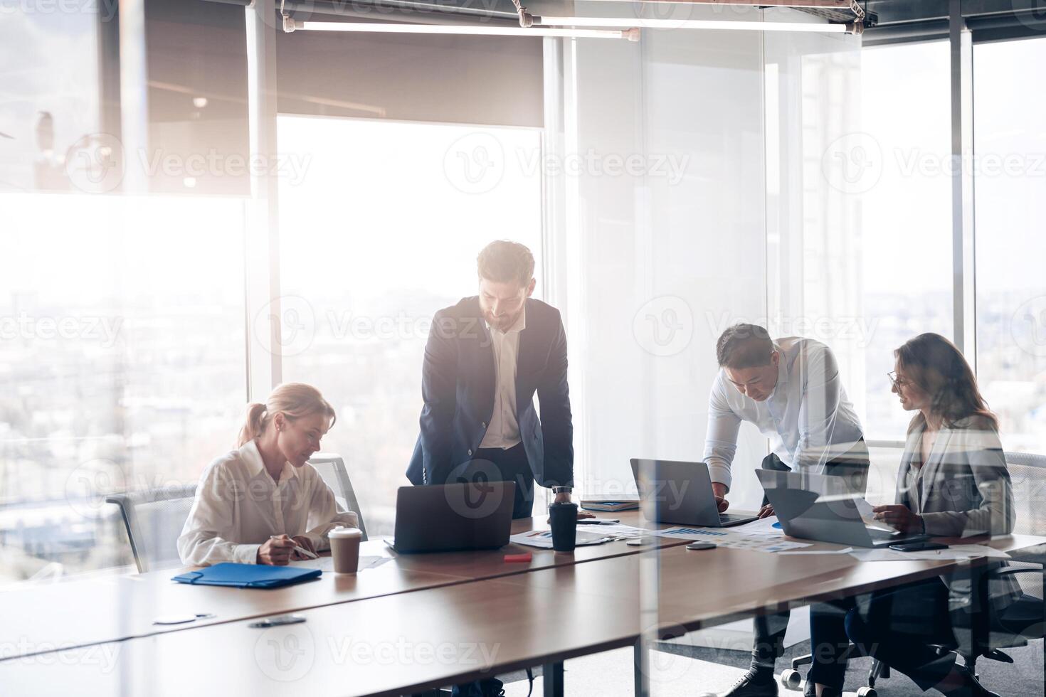 Team of young businessmen working and communicating together in office with panoramic windows photo