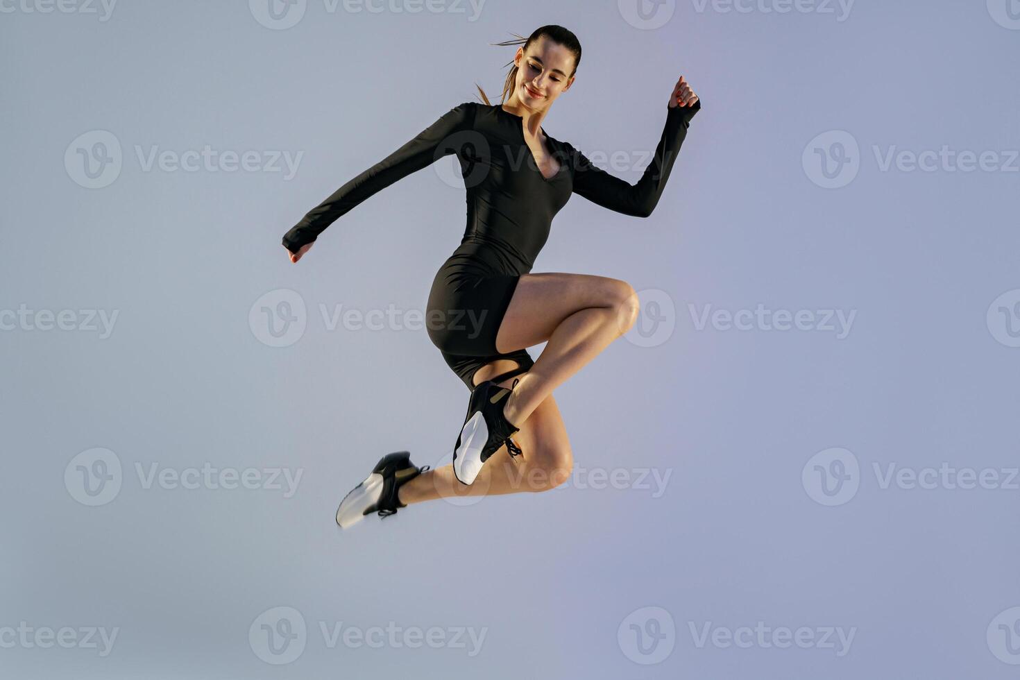 Smiling sporty woman in sportswear jumping on studio background. Sport and healthy lifestyle photo