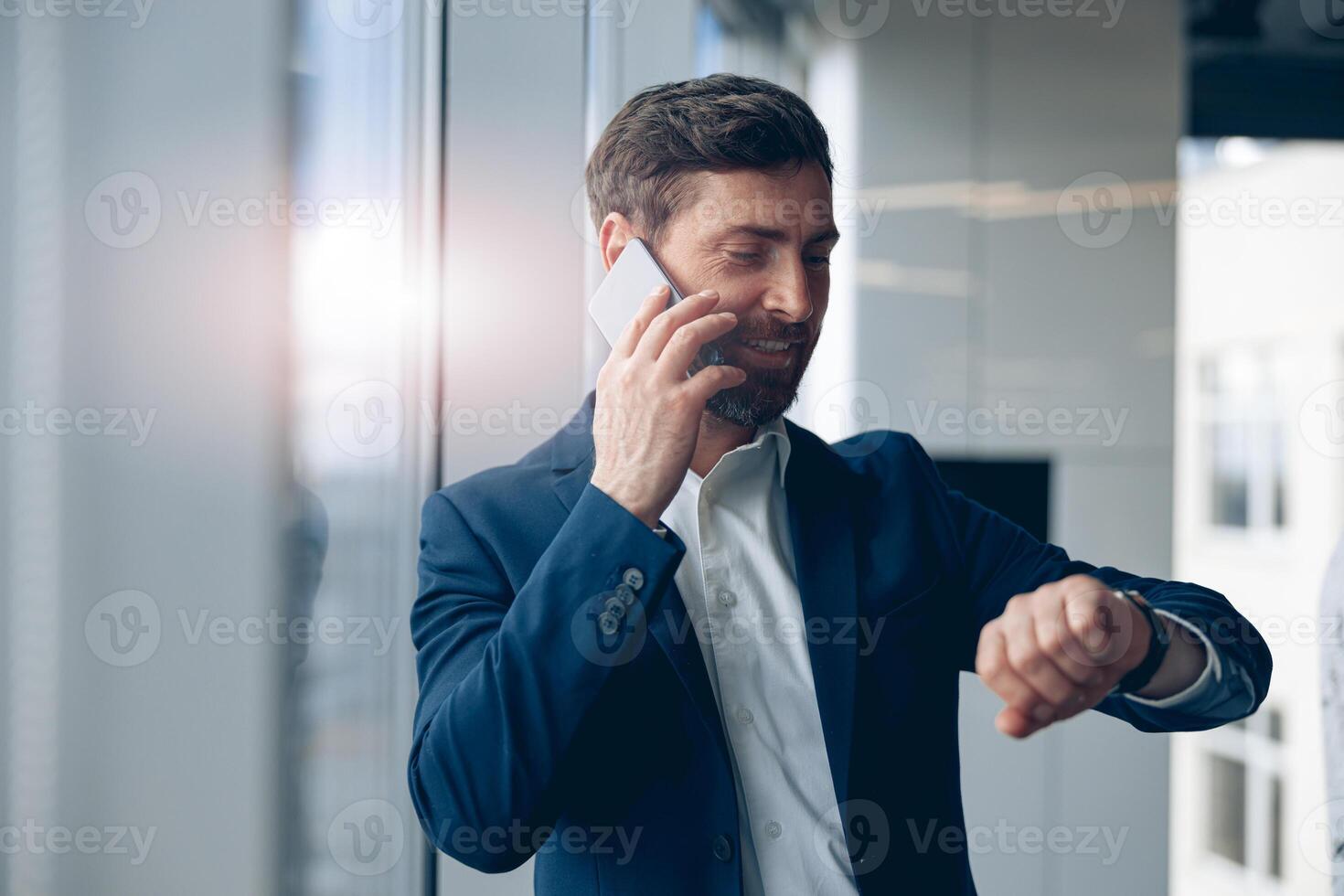 businessman looking at his wrist watch and talking mobile phone with business partner photo