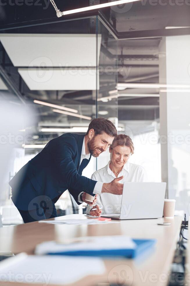 Happy employee showing presentation to mature female boss for discussing online project photo