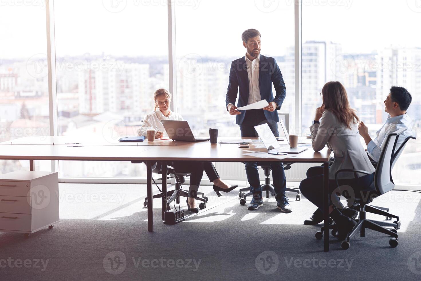 people standing near table, team of young businessmen working and communicating together in office photo