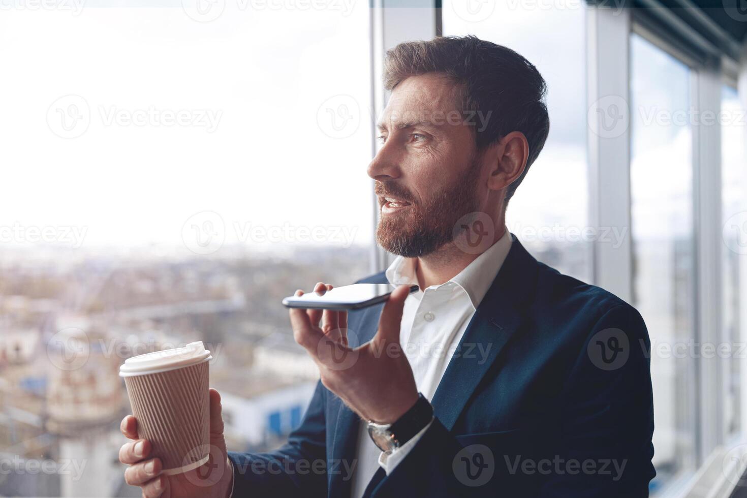 Focused businessman is using smartphone to record a voice message to business partner photo