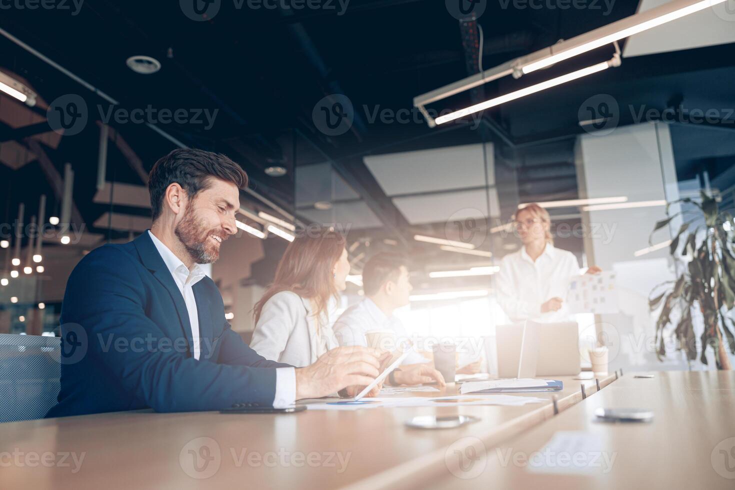 Creative smiling businessman working on a tablet during a meeting with a team photo