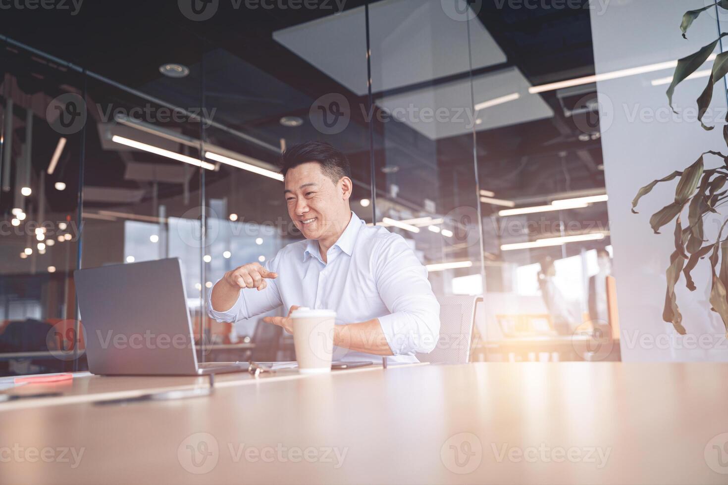 Happy Asian businessman communicating in call with deaf client at workplace in modern office photo