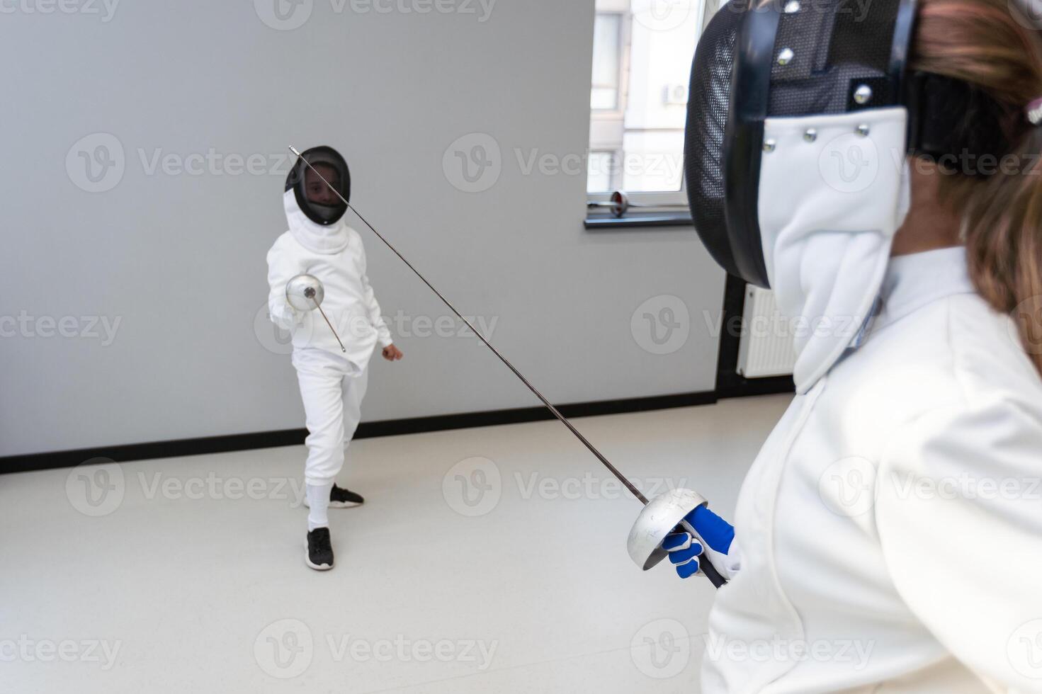 Children lunge on swords. A child in a class at a fencing school photo