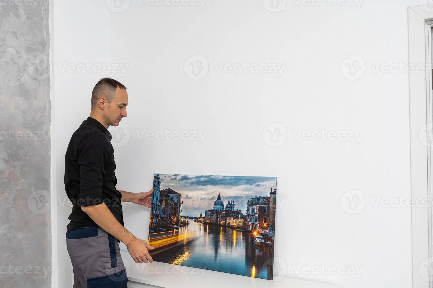 hombre colgando imágenes en el muro, limpieza y remodelación departamento. foto