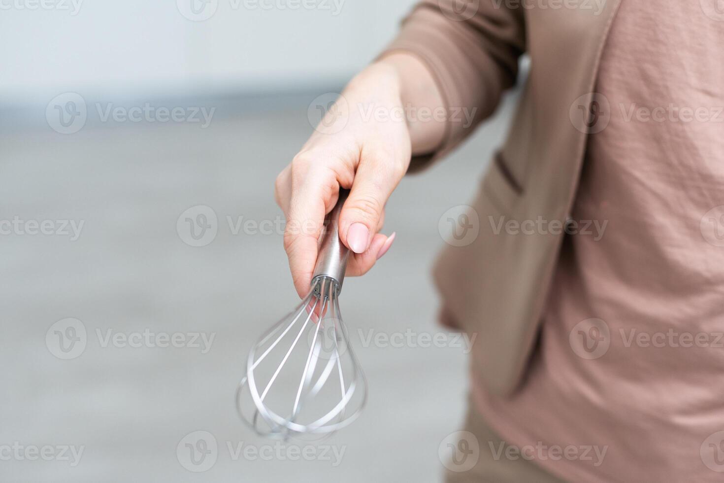 Female holding in hand whisk isolated on white background. Clipping Path. Full depth of field. photo
