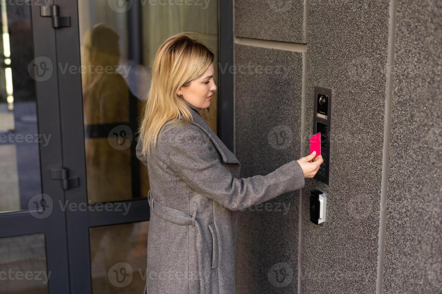 Close up of woman using card intercom at building entrance. photo