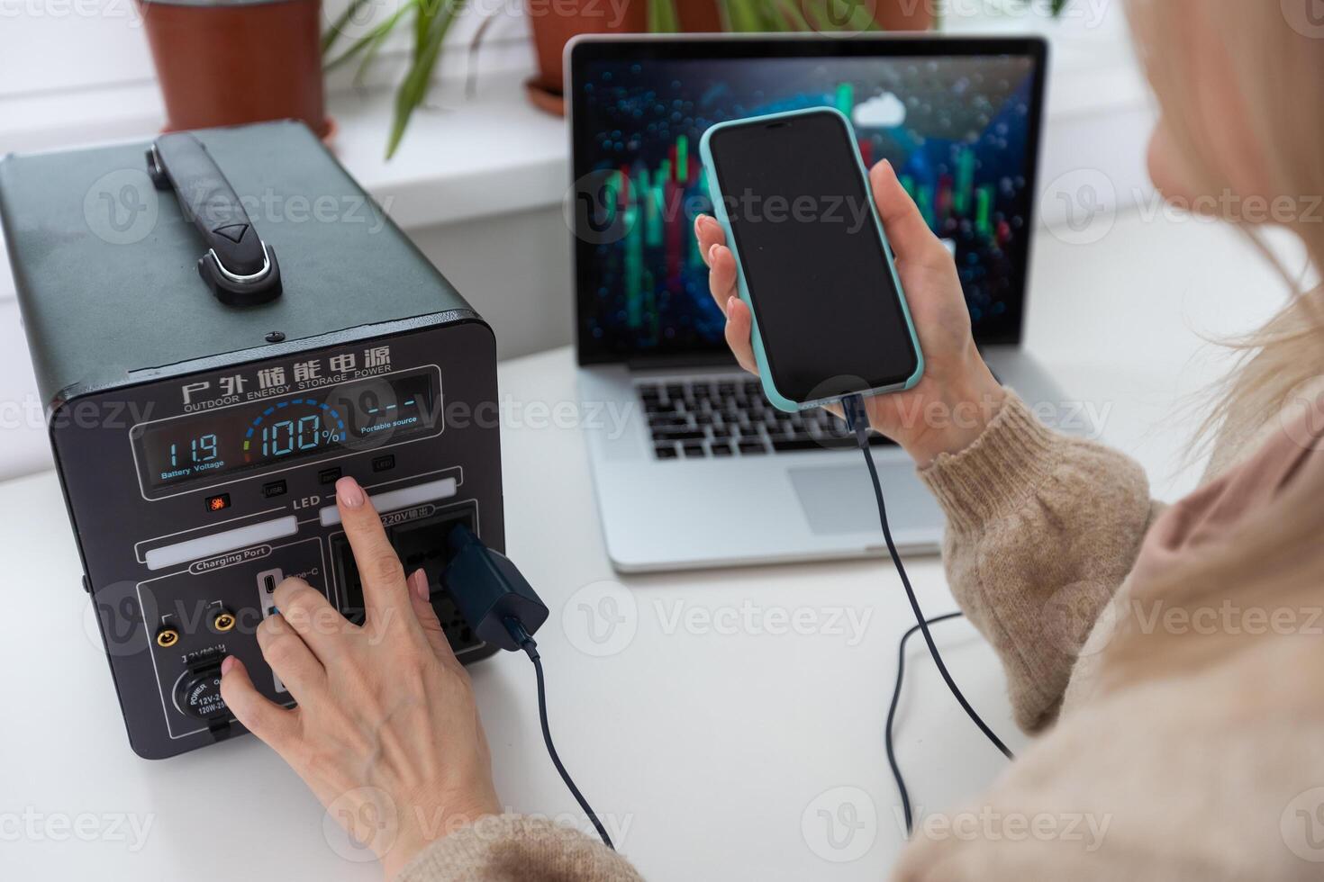 Woman inserting plug of portable solar station into socket at home photo