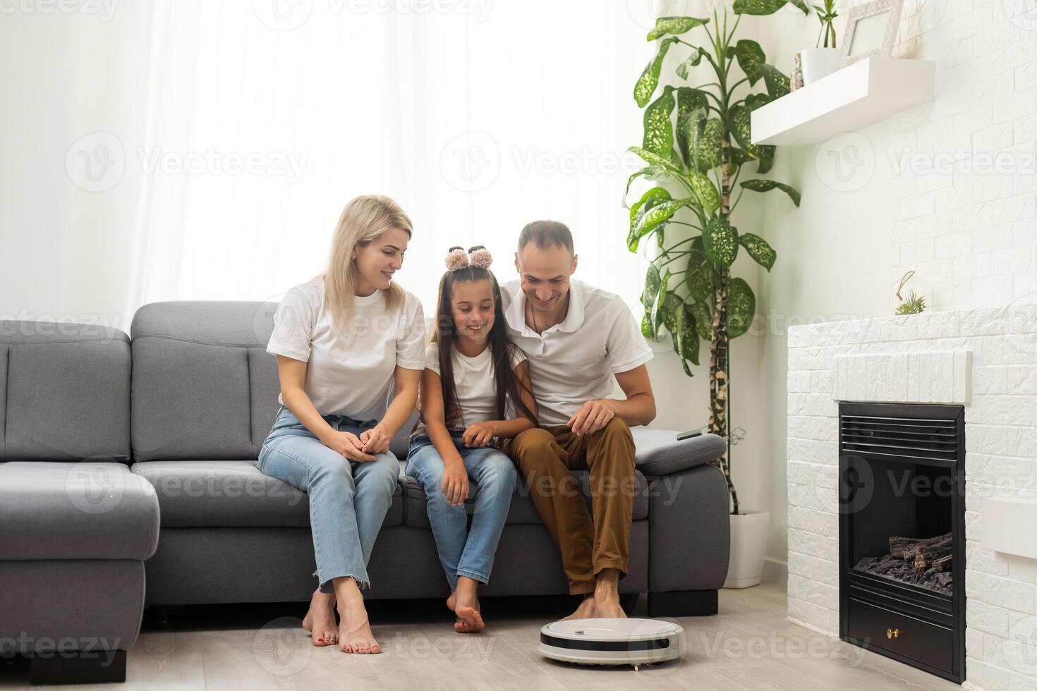 Family resting while robotic vacuum cleaner doing its work at home photo