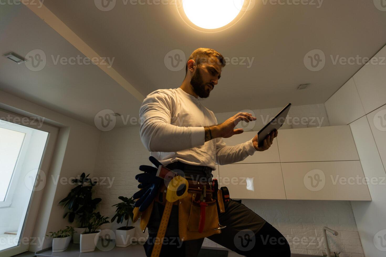 Electrician with tablet indoors, lamp photo