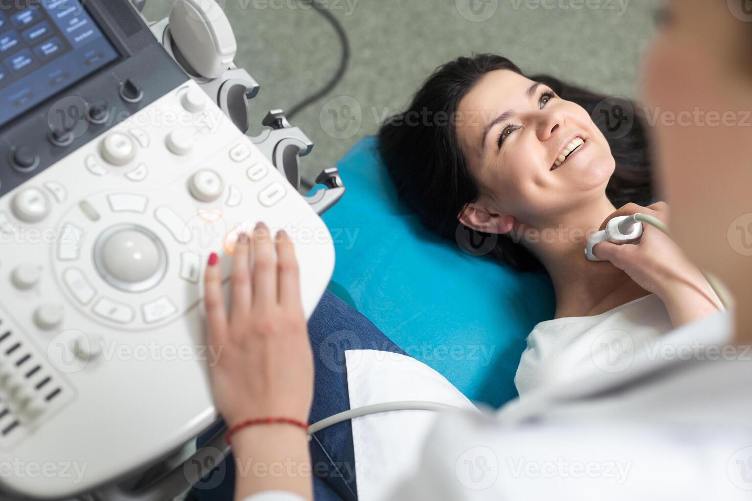 Doctor using ultrasound scanning machine for examining a thyroid of woman. photo