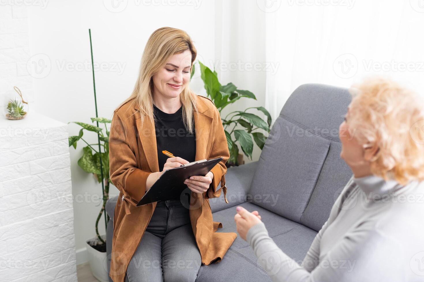 Depressed senior woman talking with female psychologist photo