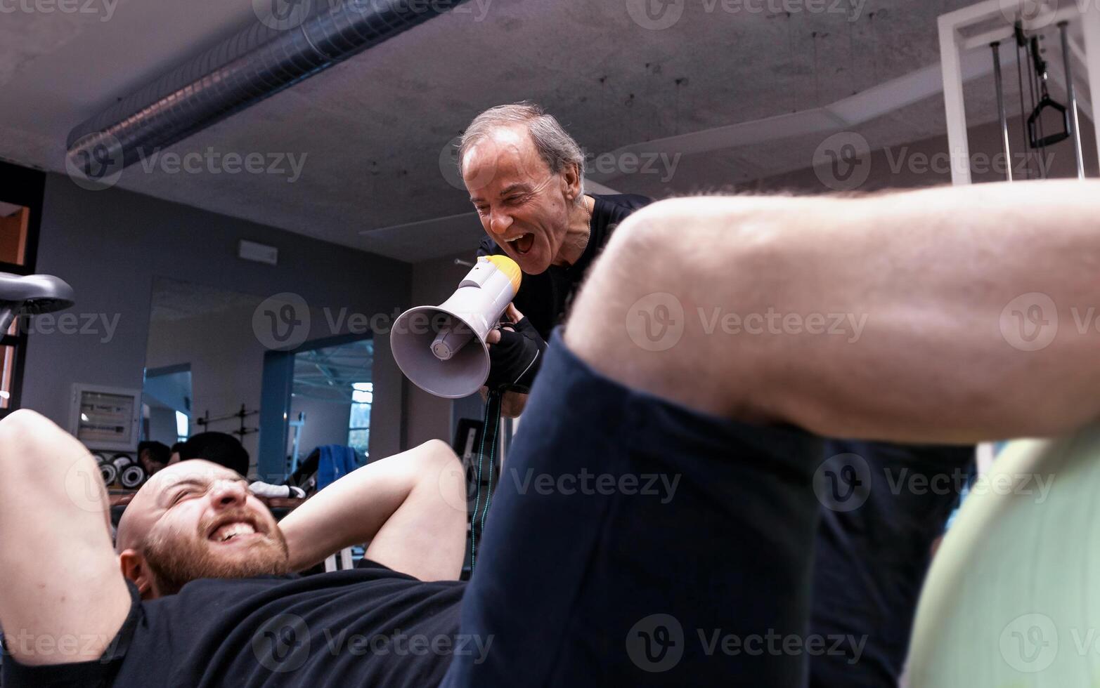 senior trainer screaming with a megaphone at the young athlete photo