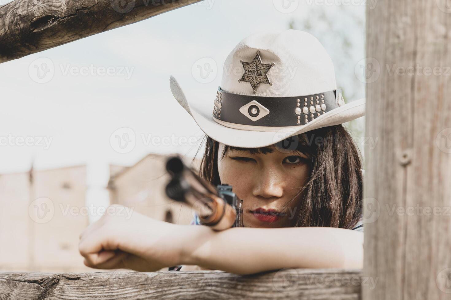 Portrait of a beautiful Chinese female cowgirl shooting with a weapon photo