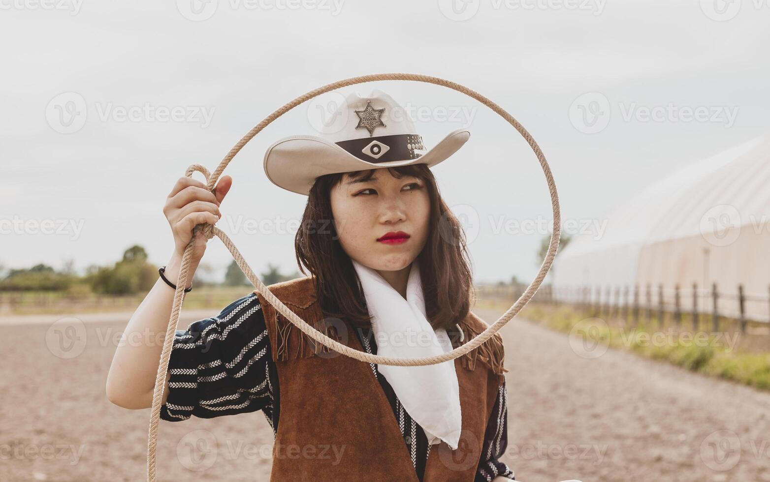 pretty Chinese cowgirl throwing the lasso in a horse paddock photo