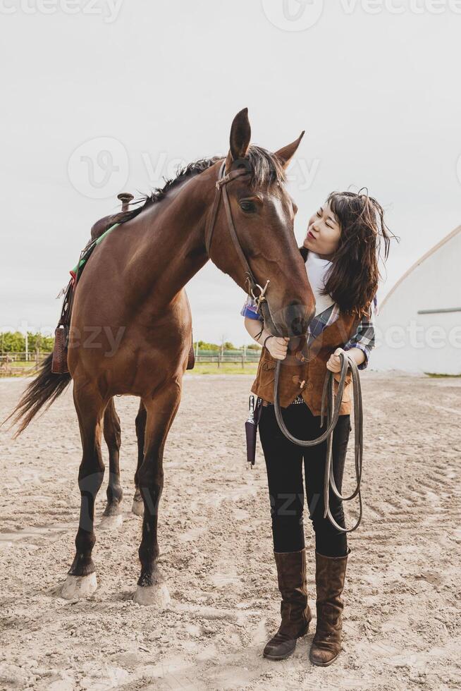 cute chinese cowgirl while taking care of her horse photo