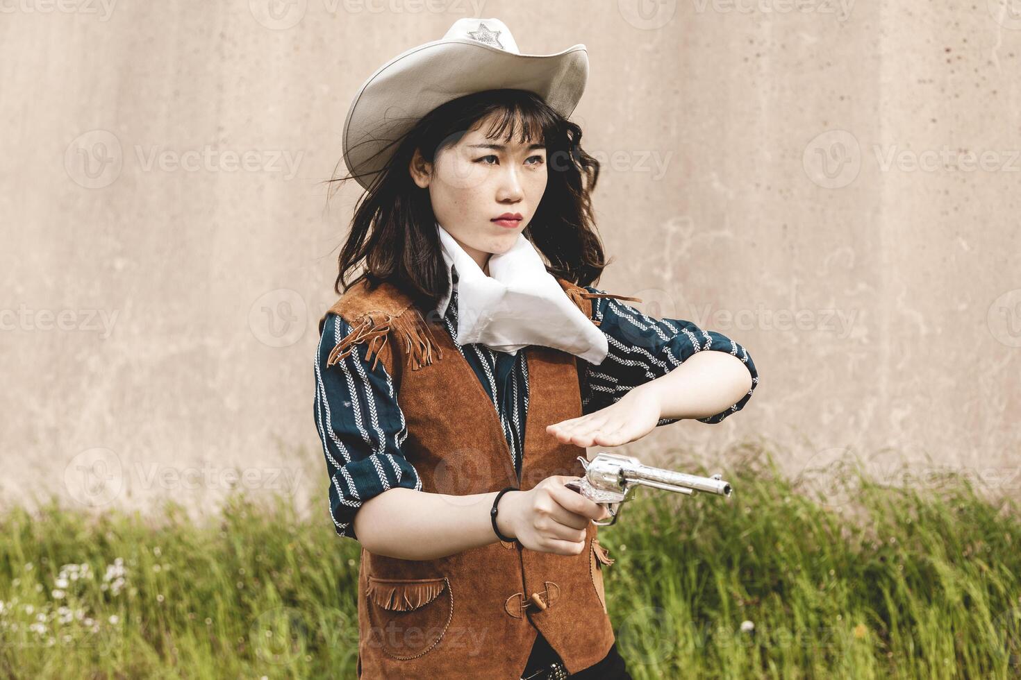 Portrait of a beautiful Chinese female cowgirl shooting with a gun photo