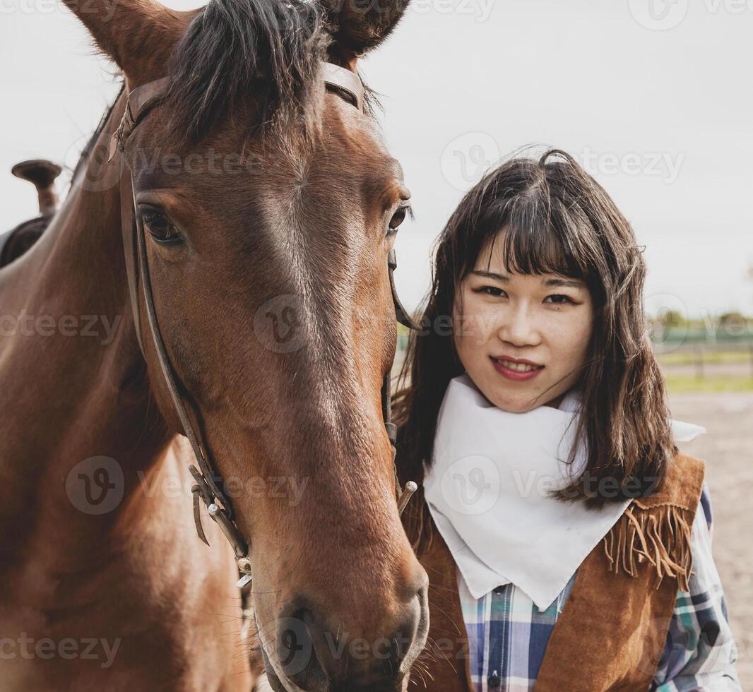 cute chinese cowgirl while taking care of her horse photo