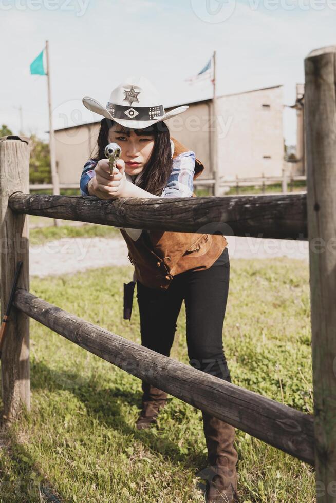 Portrait of a beautiful Chinese female cowgirl shooting with a weapon photo