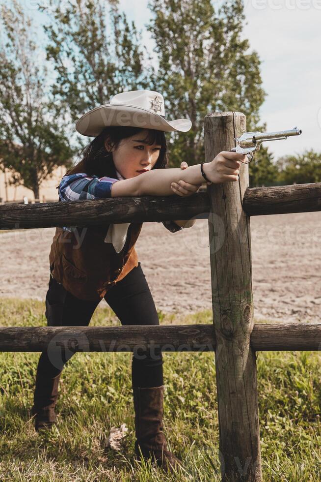 Portrait of a beautiful Chinese female cowgirl shooting with a weapon photo