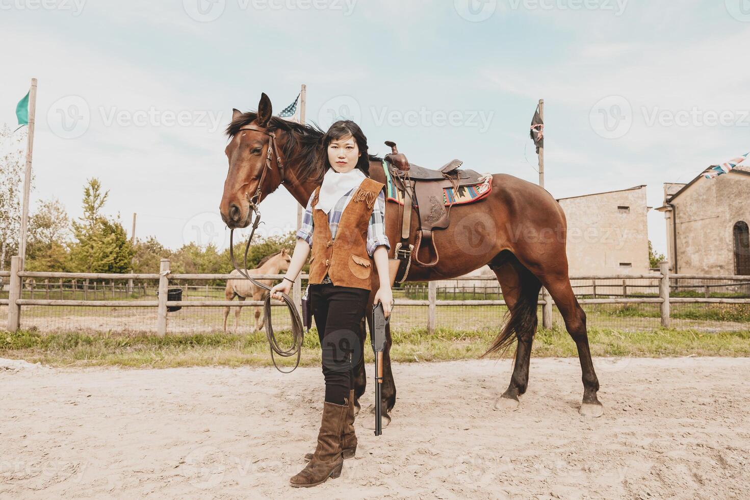 cute chinese cowgirl while taking care of her horse photo