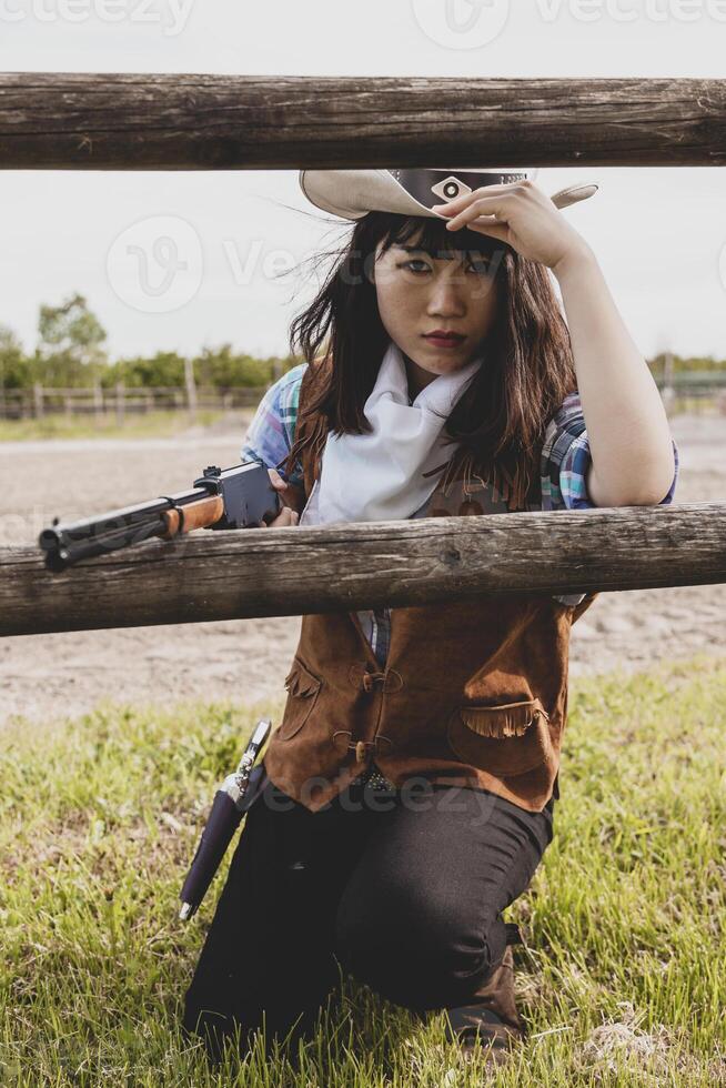 Portrait of a beautiful Chinese female cowgirl shooting with a weapon photo