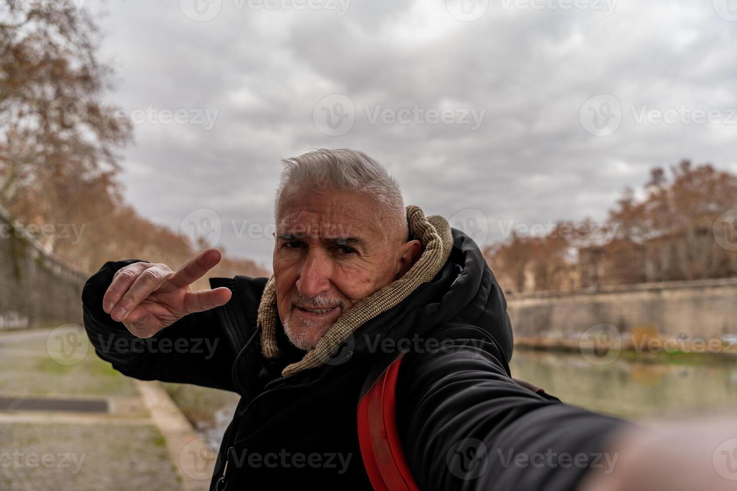 contento medio Envejecido hombre en vacaciones tomando un selfie en el bancos de el tiber río en Roma foto