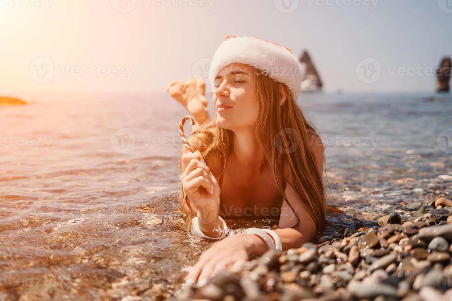 Woman travel sea. Happy tourist enjoy taking picture on the beach for memories. Woman traveler in Santa hat looks at camera on the sea bay, sharing travel adventure journey photo