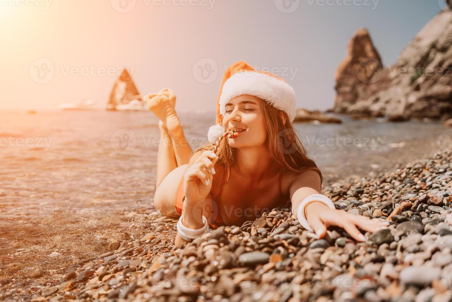 Woman travel sea. Happy tourist enjoy taking picture on the beach for memories. Woman traveler in Santa hat looks at camera on the sea bay, sharing travel adventure journey photo