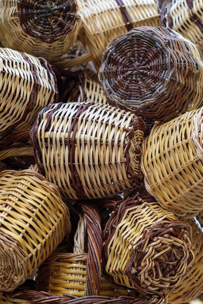 Closeup on group of handmade wicker rustic baskets container for shopping. Natural colors and texture. Eco concept. Wooden hanging wicker pots. Traditional greek street shop. Vertical. Soft focus photo