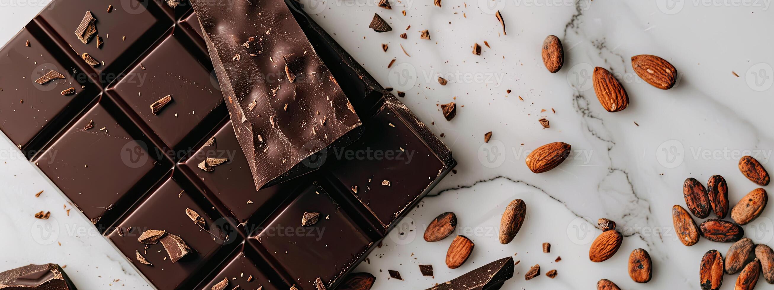 Chocolate bar with cacao beans and almonds scattered around it photo