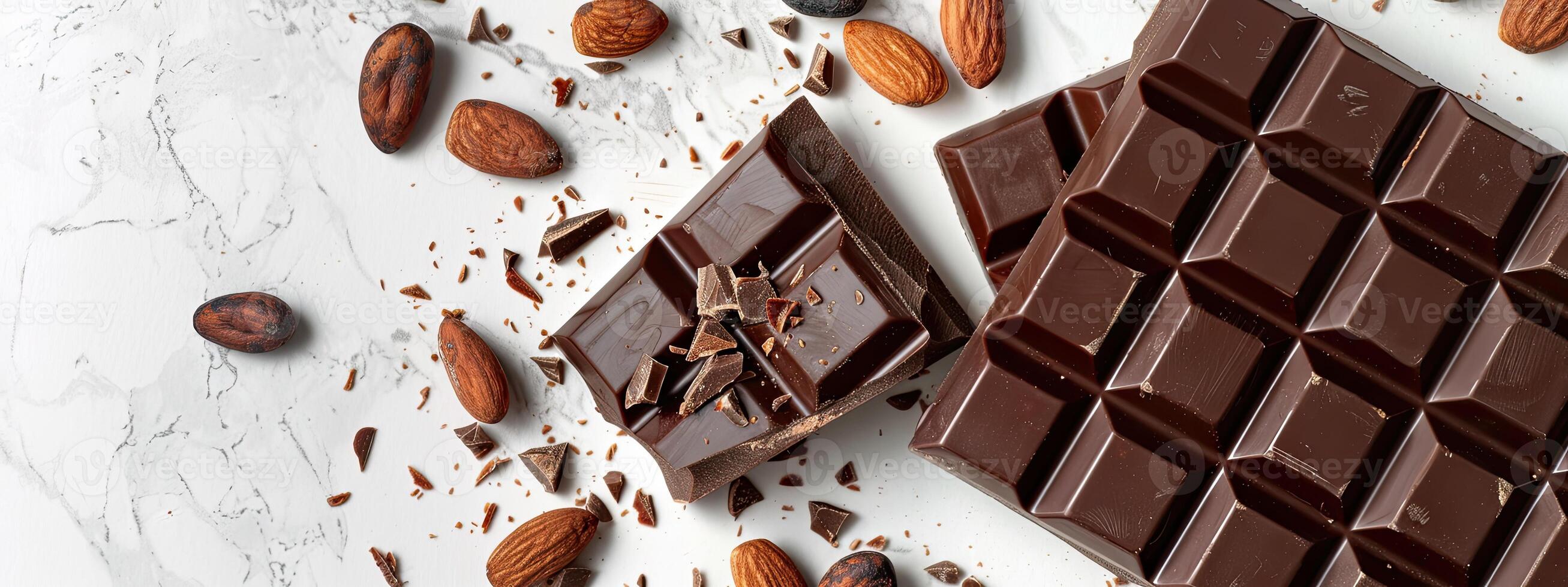 Chocolate bar with cacao beans and almonds scattered around it photo