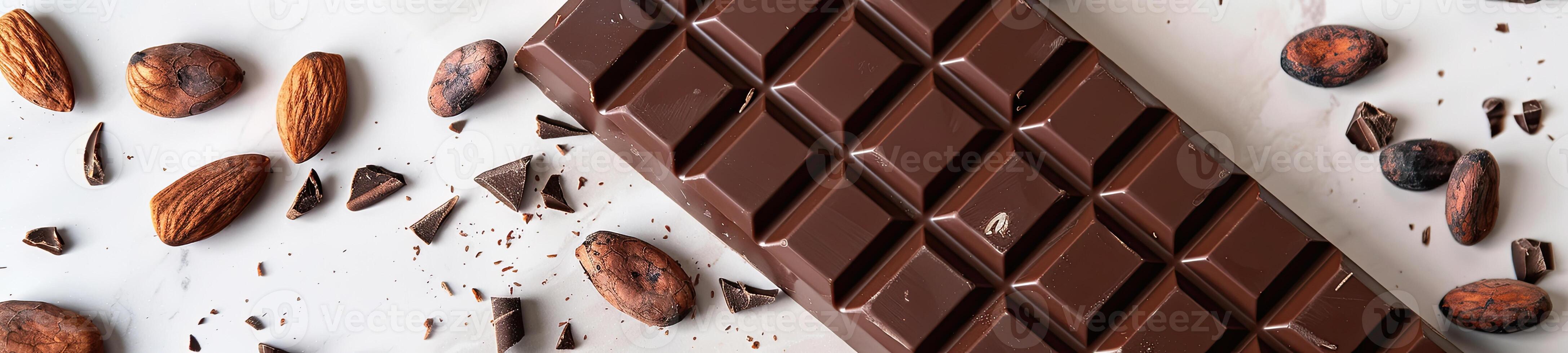 Chocolate bar with cacao beans and almonds scattered around it photo