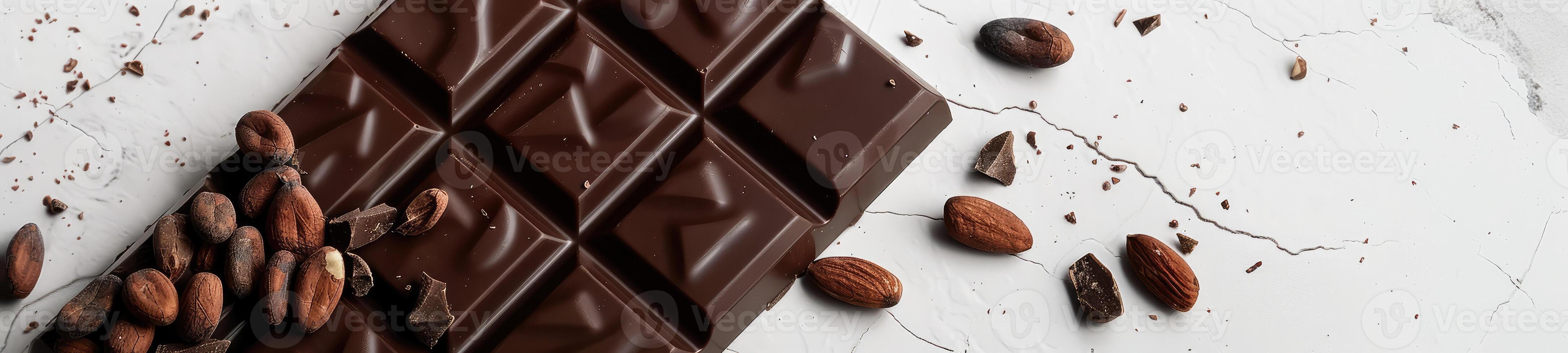 Chocolate bar with cacao beans and almonds scattered around it photo