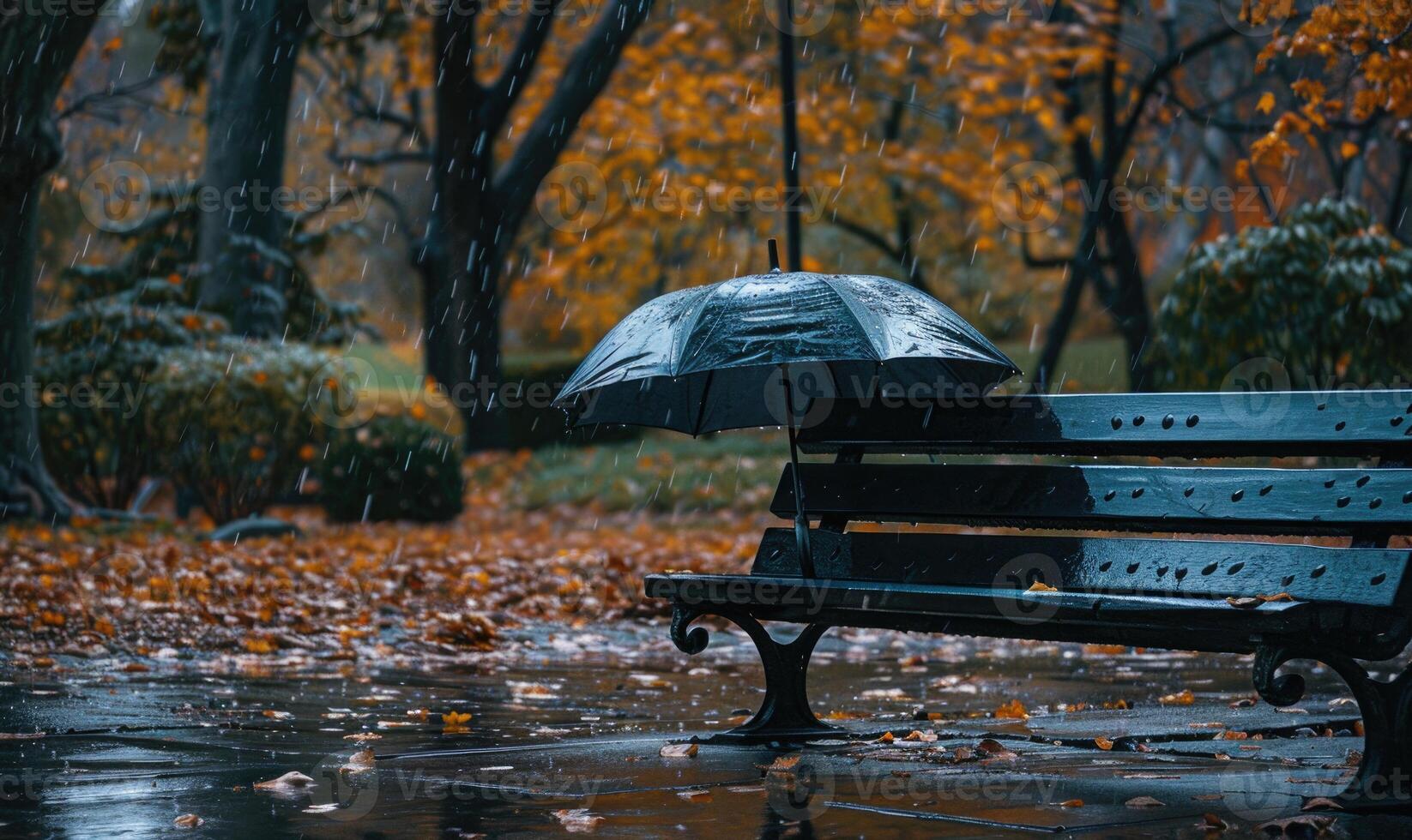 A lone umbrella on a wet park bench during in the rain photo